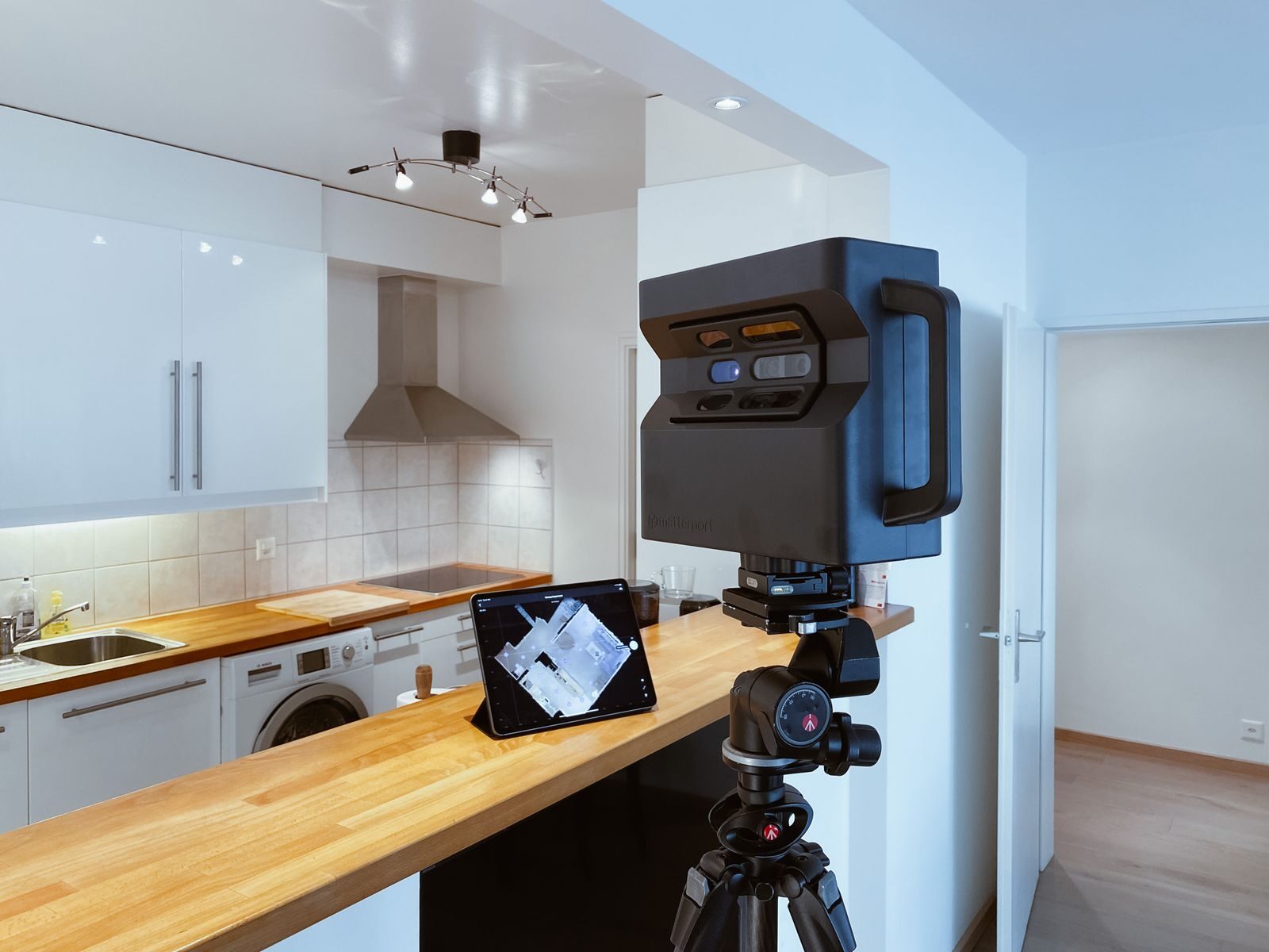 Modern kitchen interior with digital scanning setup on tripod, highlighting sleek design and technology integration.